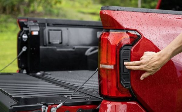 Задните светлини на Tacoma включват страхотен скрит трик - алуминиевата задна врата ще се предлага с опционална функция за отваряне/затваряне, която обикновено е запазена за пълноразмерни пикапи. Tacoma ще е единственият от среден размер, който предлага такова удобство. Електрическата задна врата може да се управлява чрез ключа или традиционната дръжка, но може да се активира и с правоъгълен бутон, интегриран в задните светлини. Задната врата дори ще започне да се повдига, ако я натиснете леко с коляно, когато ръцете ви са заети.